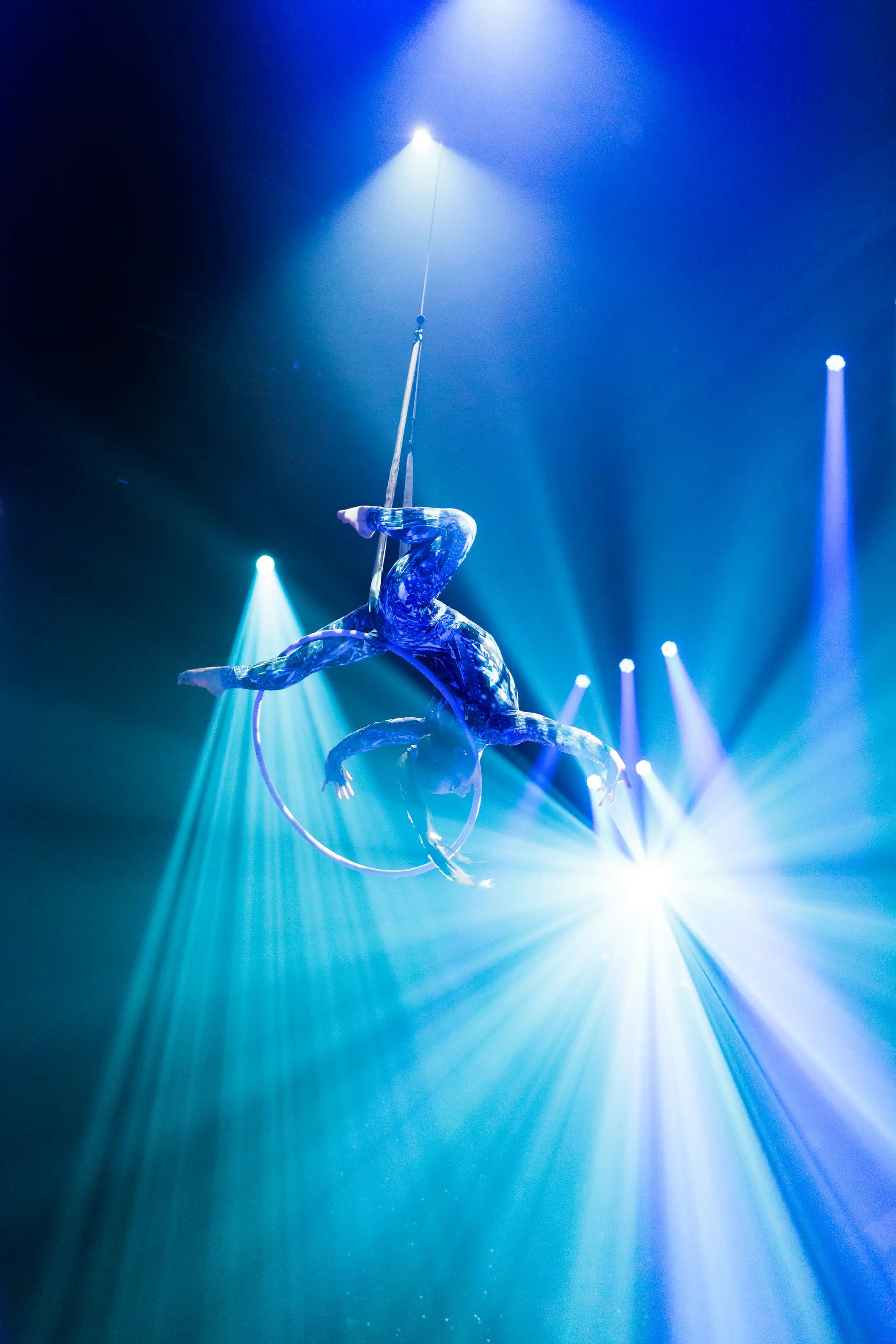 IBM — An aerialist in a hoop under blue stage beams